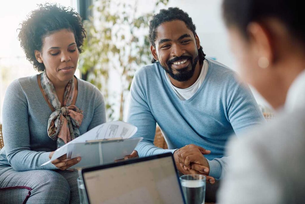 A couple reviews a life insurance denial letter and medical records at a kitchen table.